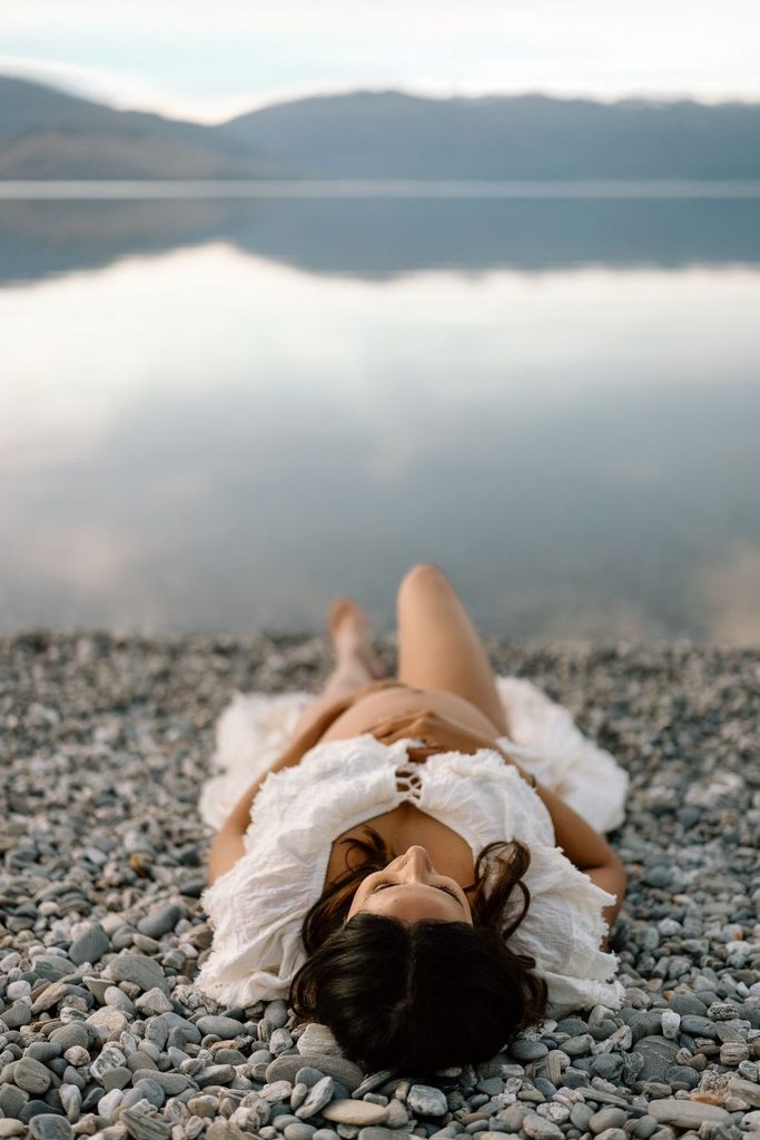Pregnant lady posing on the lake shore in Lake Wanaka, New Zealand for her maternity shoot