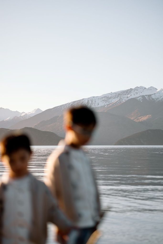 Two boys at at Lake Wanka with snowy mountains in the background