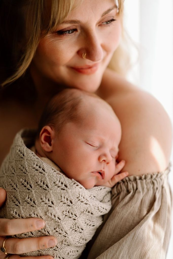 mum holding her newborn baby during a newborn photoshoot in Lake Hawea