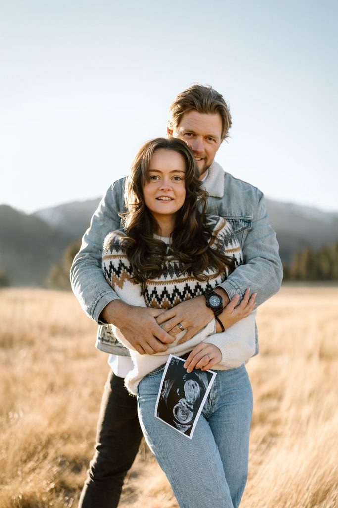 Expecting couple in the field during their pregnancy announcement photoshoot at Lake Hawea, New Zealand.