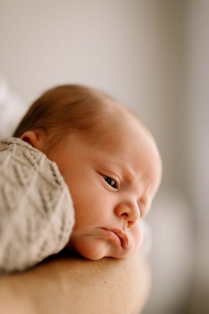 Newborn baby resting on dads arm during newborn photoshoot in Wanaka.